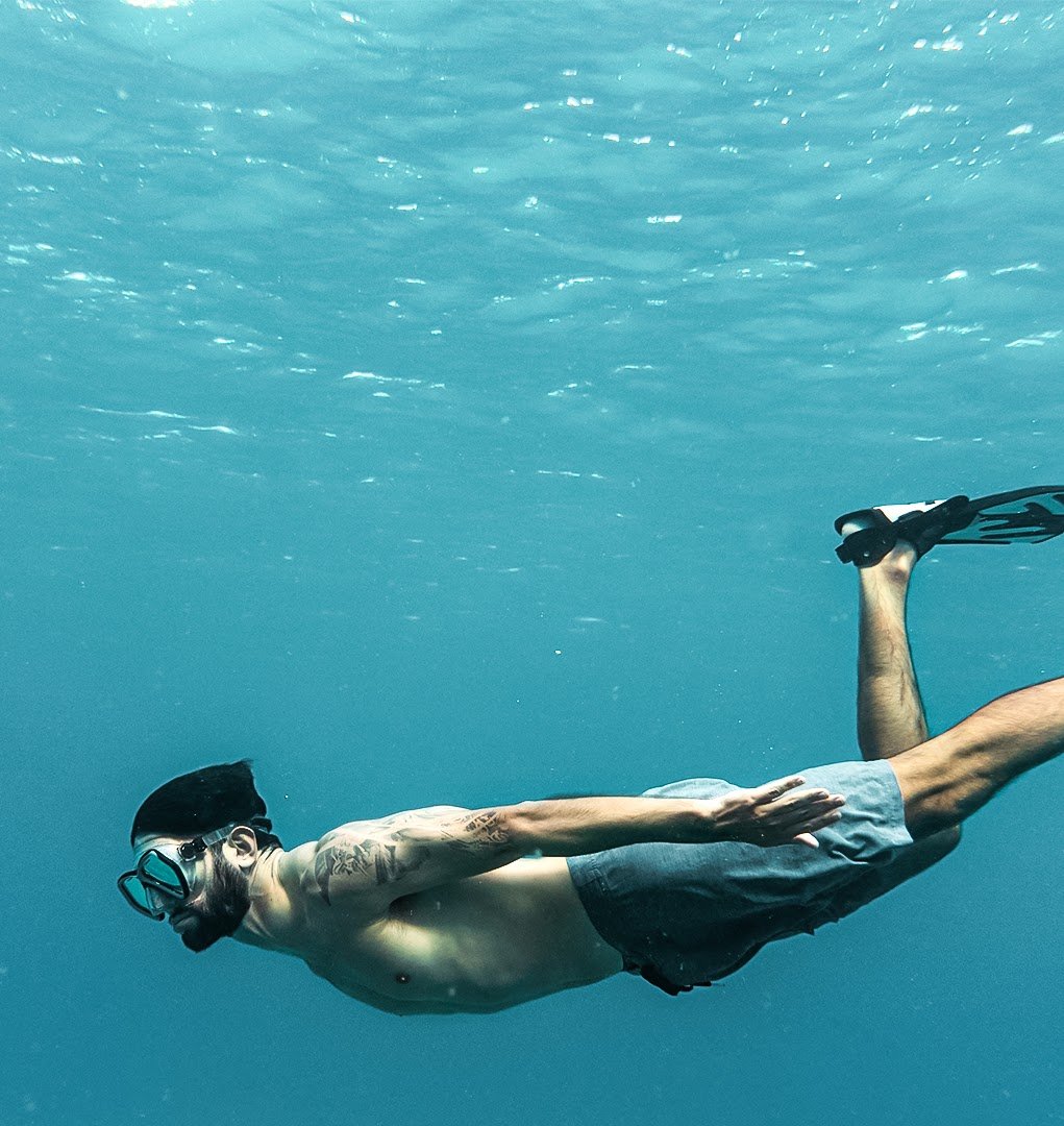 A freediver moves through deep blue water &mdash; a metaphor for returning to the human experience.